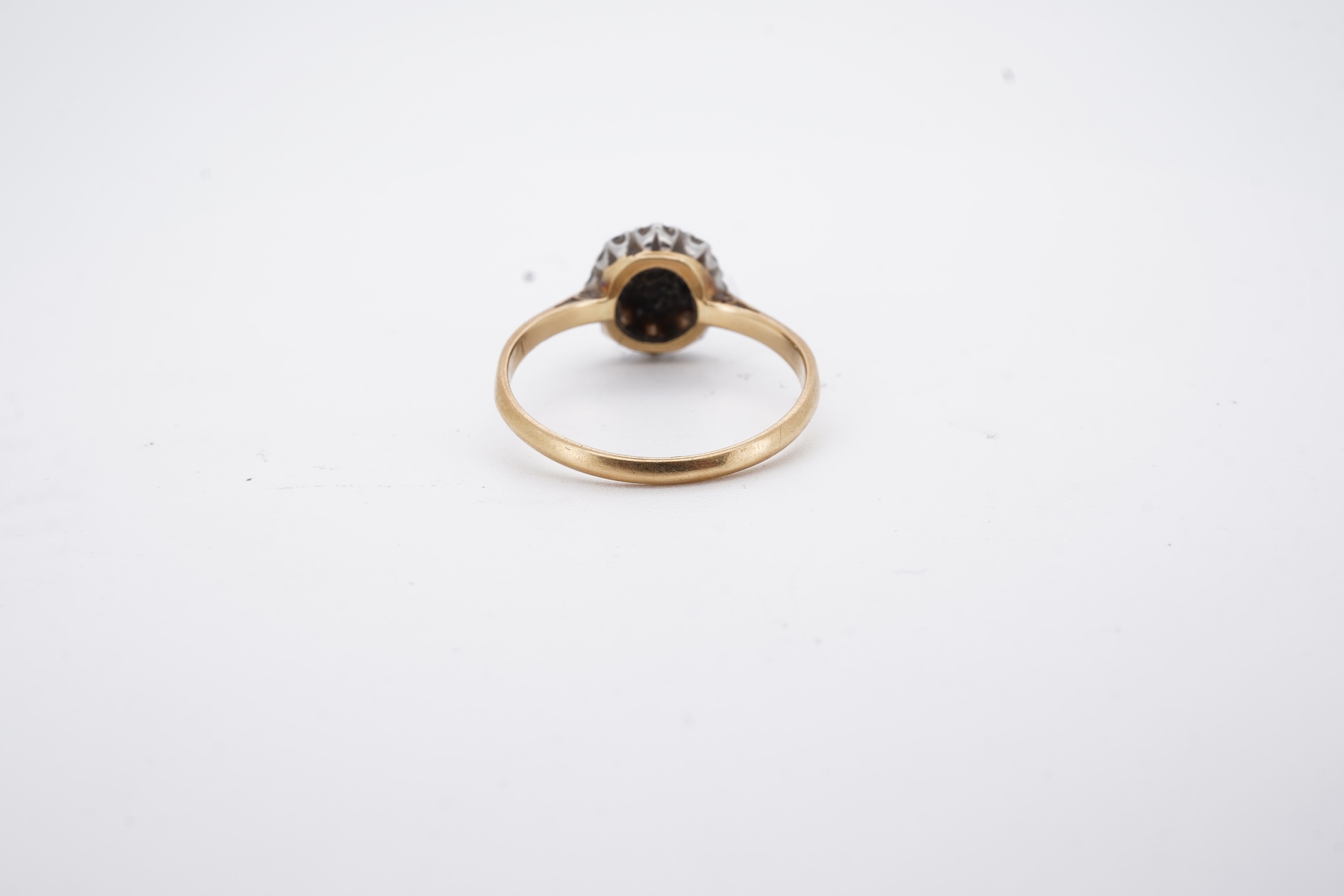 An early 20th century 18ct, plat. and nine stone diamond cluster ring, the central diamond weighing approximately 0.30ct, size Q, gross weight 3.1 grams.